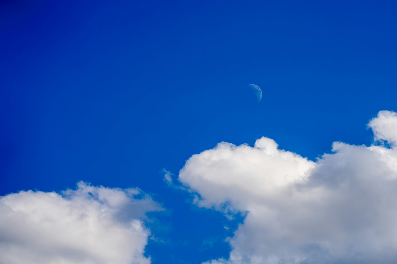 Croissant de lune dans un ciel bleu nuageux.