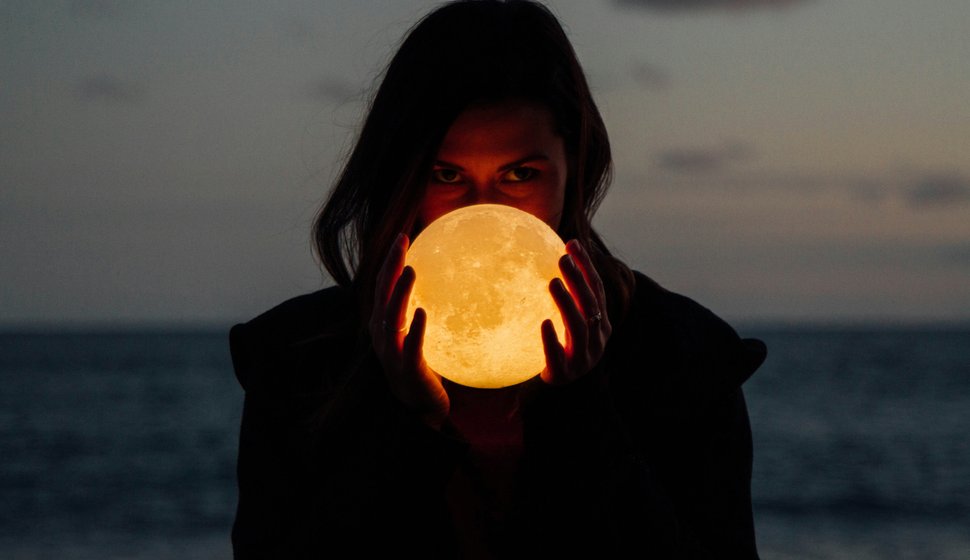 Femme tenant une lampe en forme de lune.